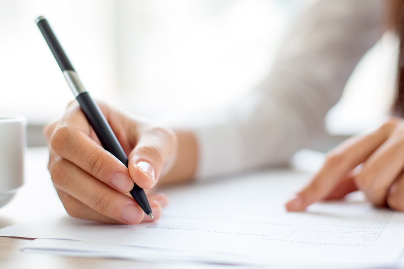 Photo d'une main tenant un stylo pour illustrer les rédaction d'acte immobilier